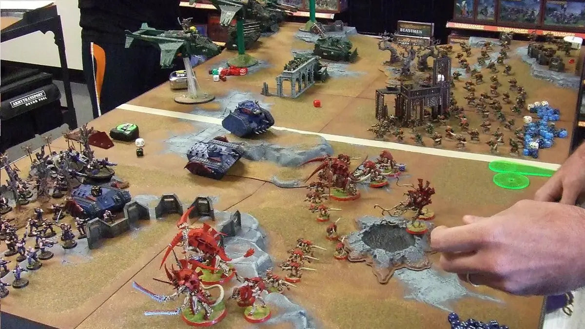 Players engage in an intense Warhammer 40k tabletop battle, featuring painted miniatures, terrain, and strategic gameplay.