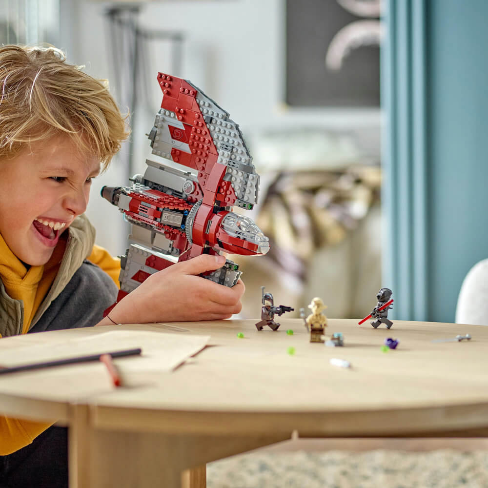 Child shown smiling and playing with the LEGO® Star Wars Ahsoka Tano's T-6 Jedi Shuttle 601 Piece Building Set (75362)
