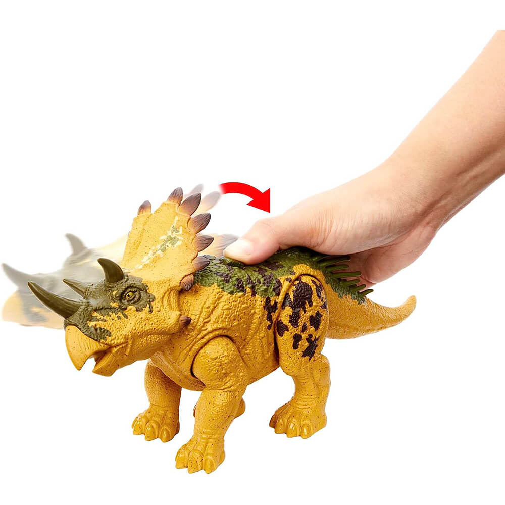 hand pushing the button on the Jurassic World Wild Roar Regaliceratops Dinosaur Figure