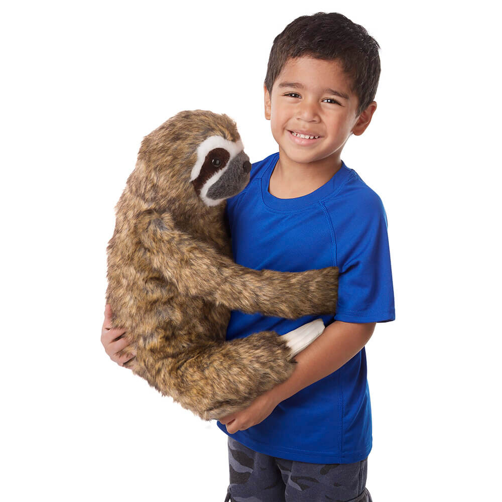 A boy hugginh the Melissa and Doug Lifelike Sloth Plush