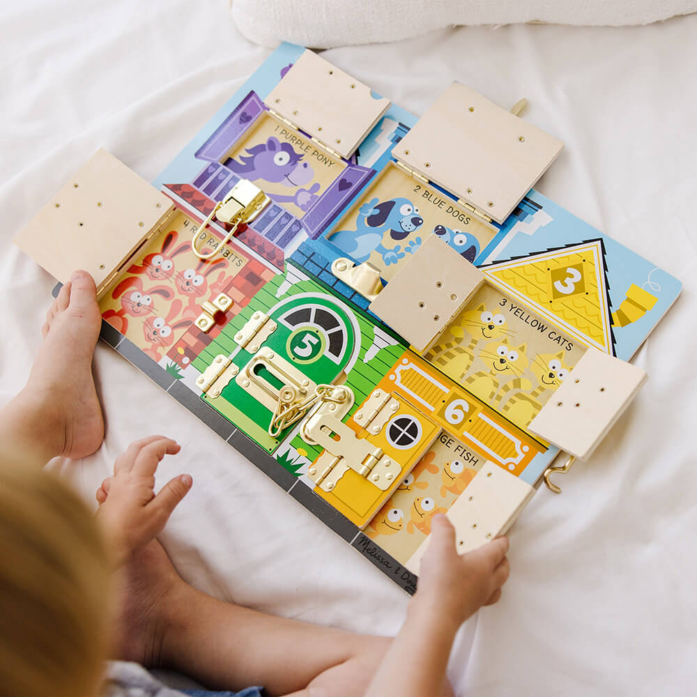 Child opening the latches on the Melissa and Doug Wooden Latches Board