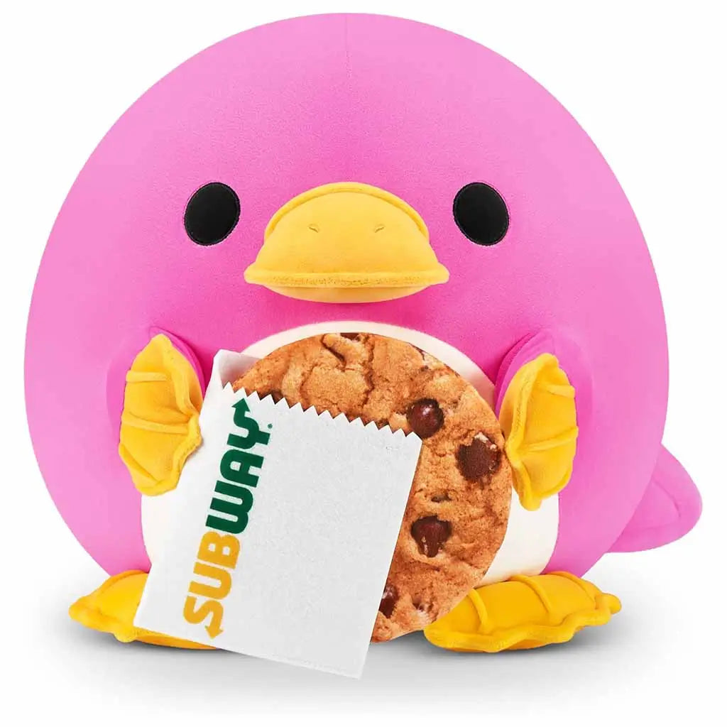 Snackles Series 2 8-inch plush toy of a pink platypus holding a Subway chocolate chip cookie wrapped in branded paper, featuring yellow beak, feet, and soft round body.