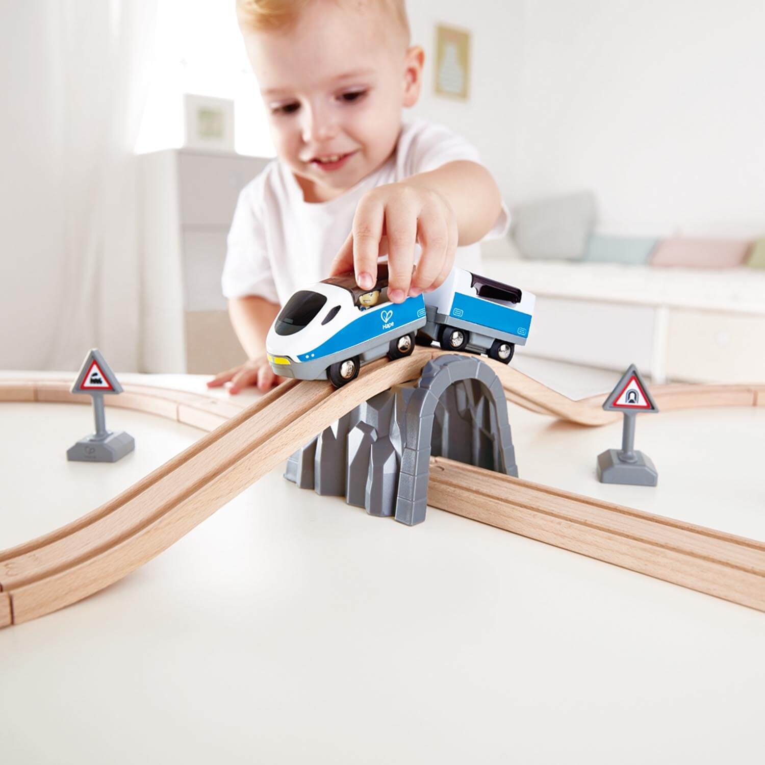 Small child playing with the Hape Railway Figure 8 Safety Wooden Train Set and pushing the train over the bridge.