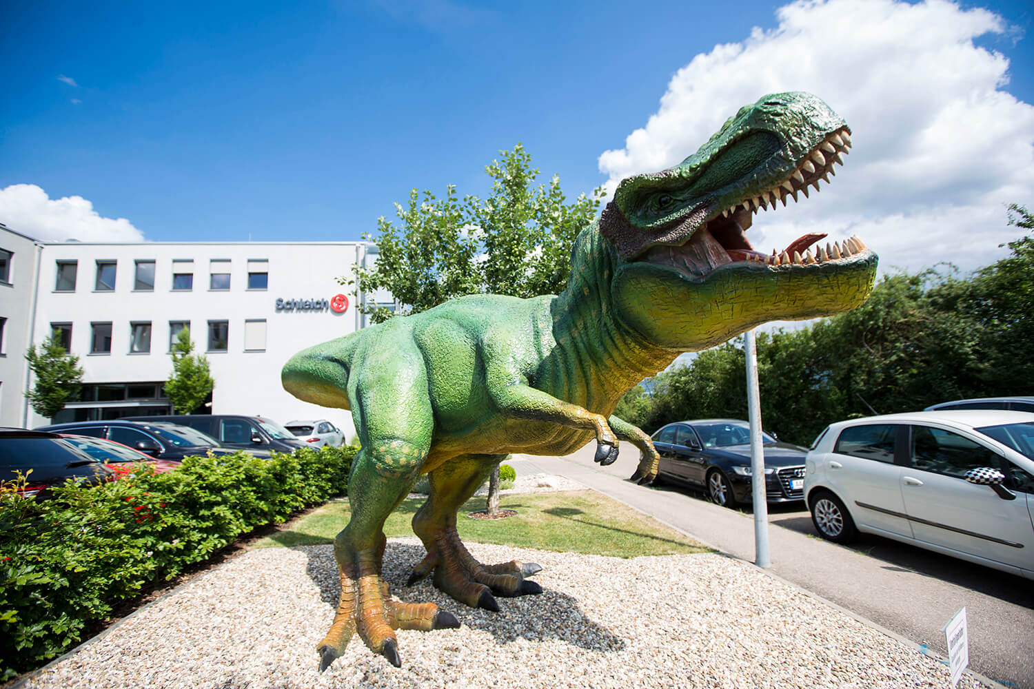 Schleich headquarters with a green life-sized T-Rex in front of the building.