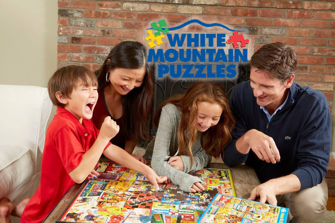 Family seated at a table and putting together a puzzle from White Mountain Puzzles.