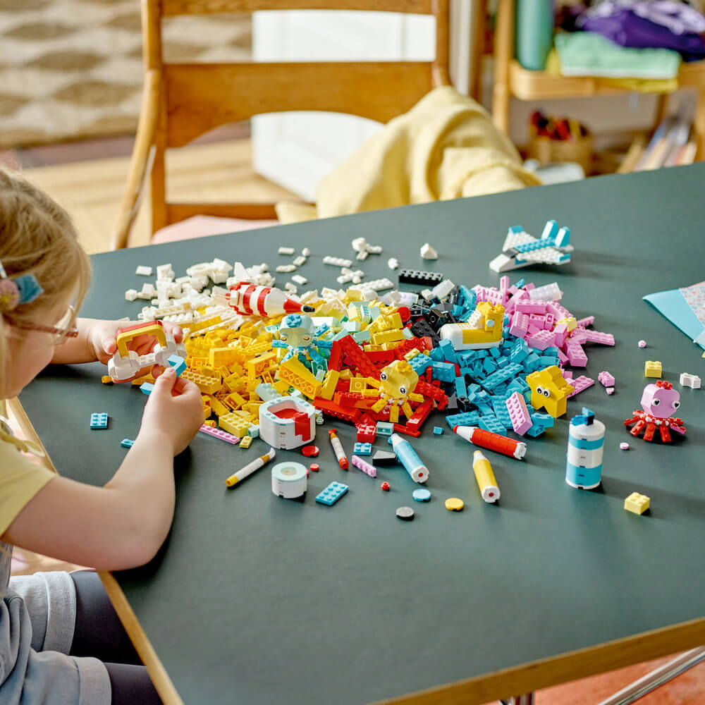 Child shown using the pieces of the LEGO® Classic Creative Color Fun 11032 Building Toy Set (1,500 Pieces) to build something