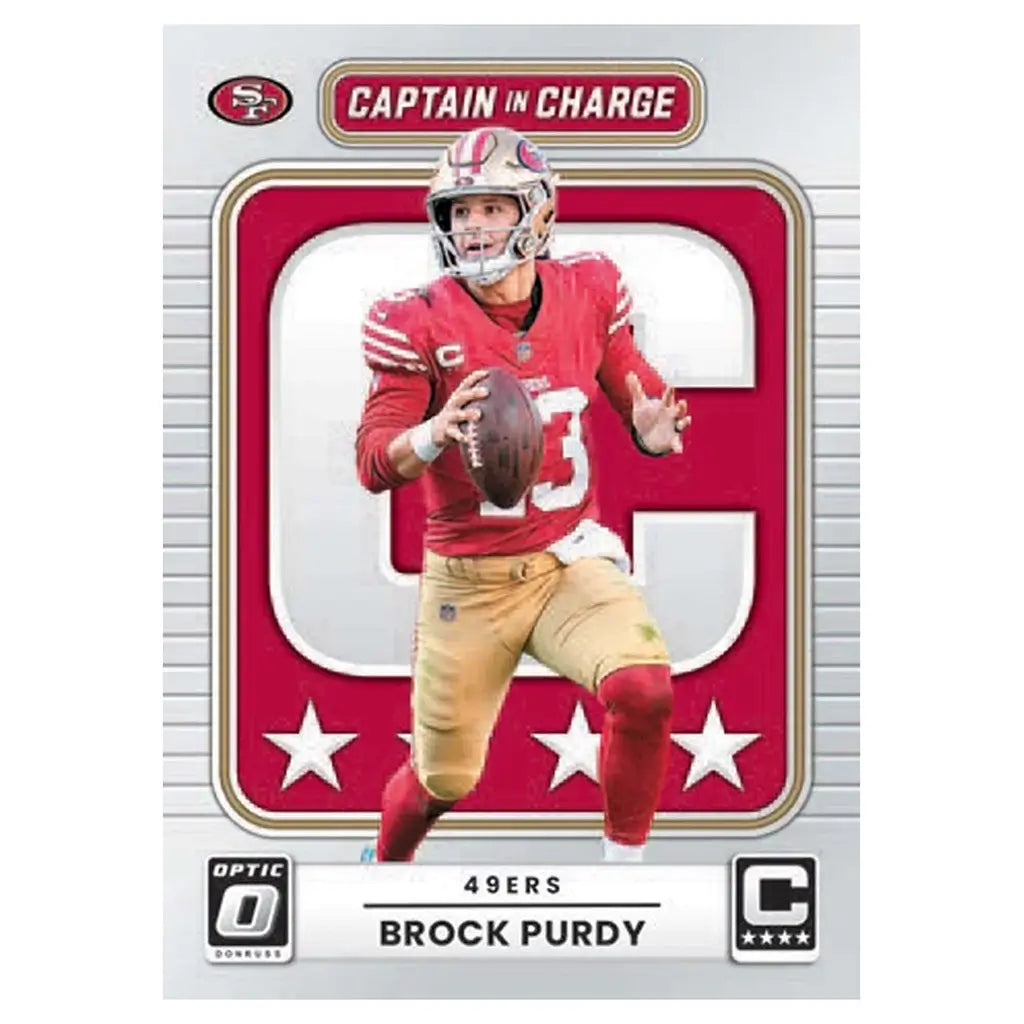 Panini Optic football card Brock Purdy red and gold printed cardstock with bold captain graphic frame, San Francisco 49ers quarterback holding ball on clean geometric background