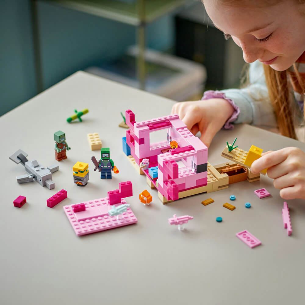 Girl smiling as she builds the LEGO® Minecraft® The Axolotl House 21247 Building Toy Set (242 Pieces)