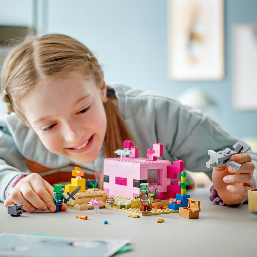 Girl is smiling as she plays with the built LEGO® Minecraft® The Axolotl House 21247 Building Toy Set (242 Pieces)