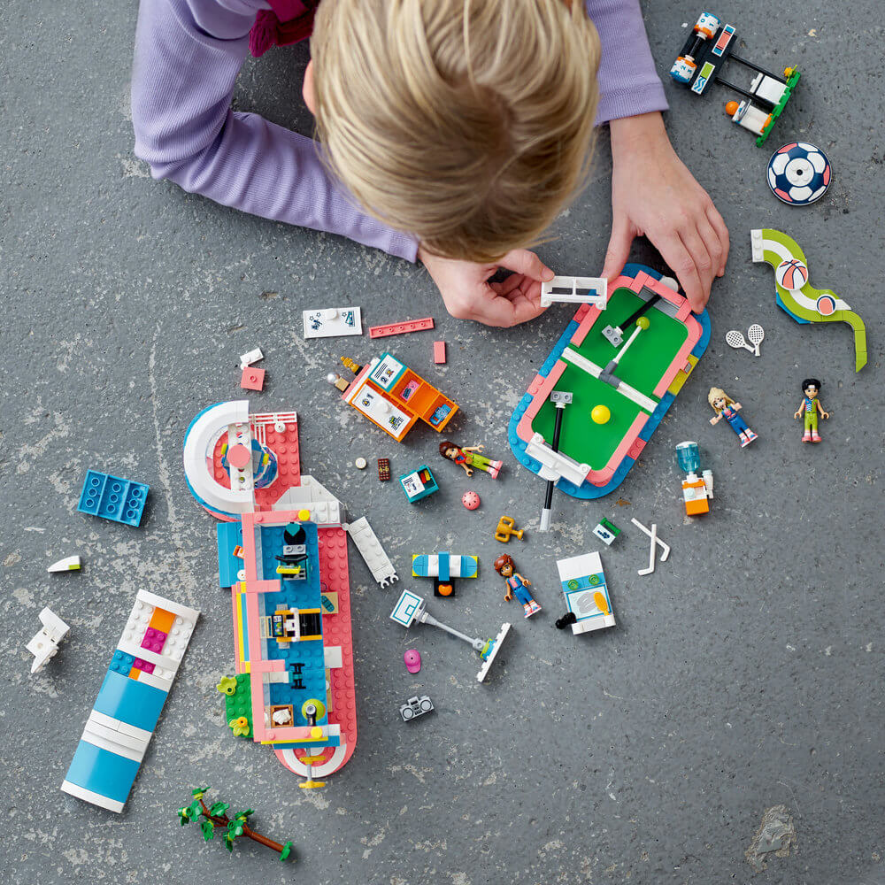 Child building the LEGO® Friends Sports Center 41744 Building Toy Set (832 Pieces)