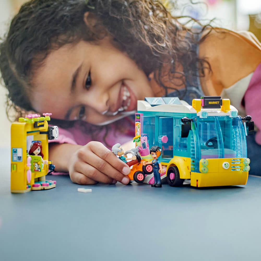 Girl playing with the LEGO® Friends Heartlake City Bus 41759 Building Toy Set (480 Pieces) built set