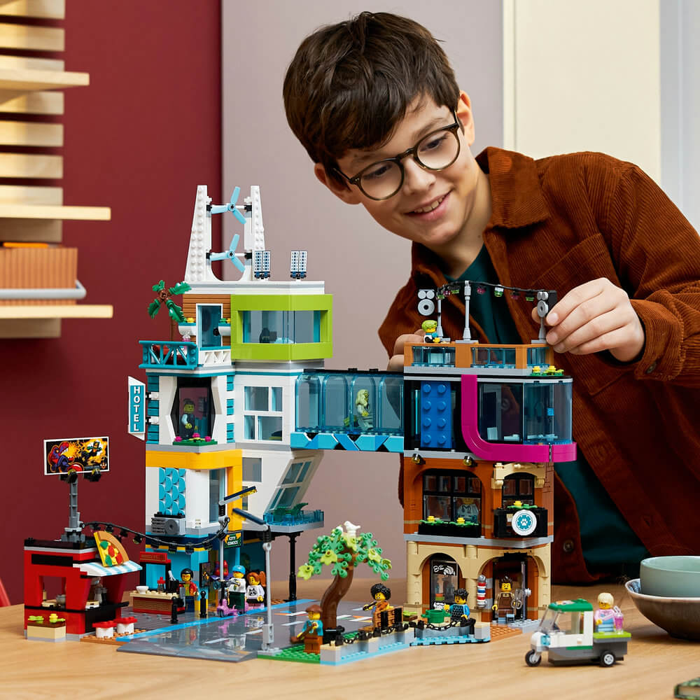 Child playing with the completed LEGO® City Downtown 60380 Building Toy Set (2,010 Pieces)