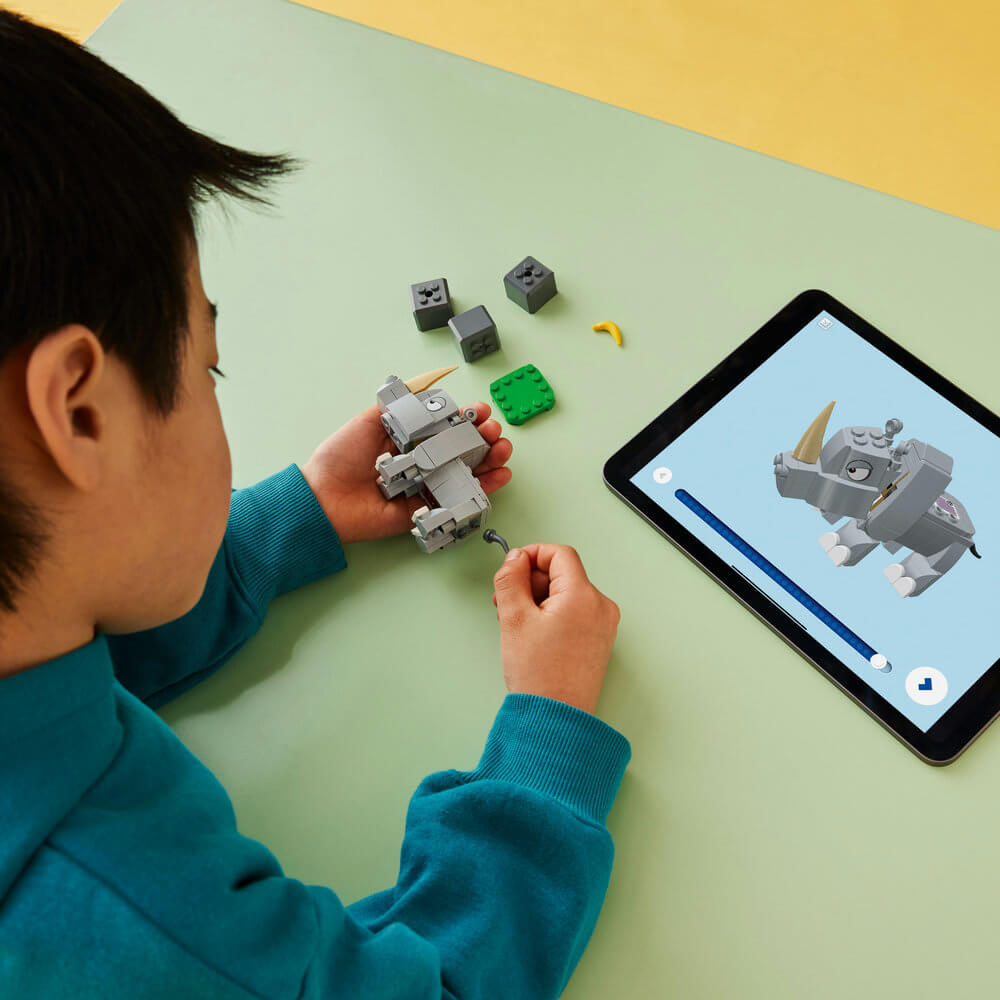Child following the directions on their tablet to build  the LEGO® Super Mario™ Rambi the Rhino Expansion Set 71420 (106 Pieces)