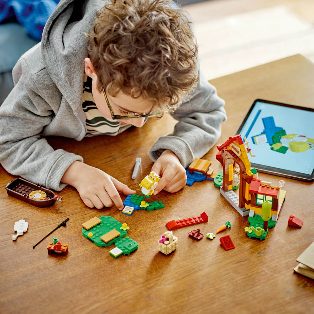 Child building the LEGO® Super Mario™ Picnic at Mario’s House Expansion Set 71422 (259 Pieces) using their tablet for the instructions