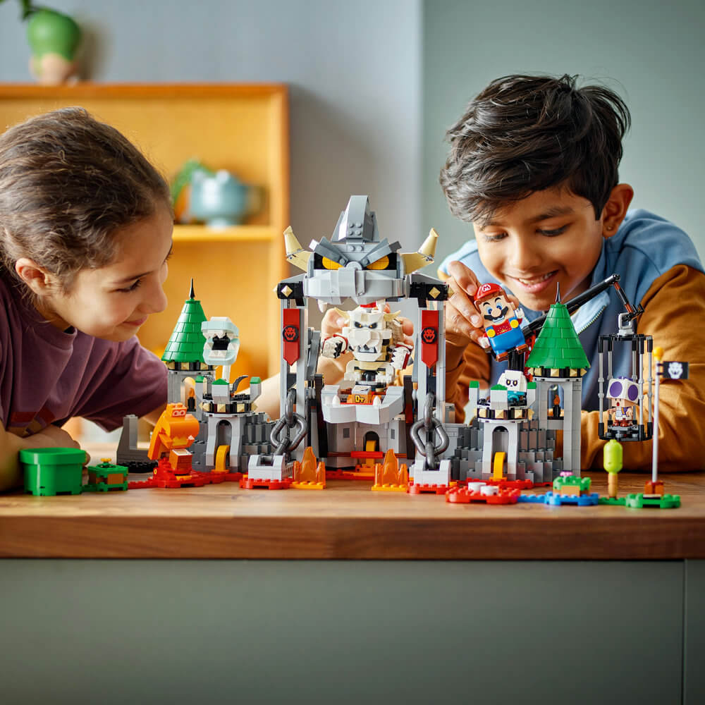 Two children playing with the LEGO® Super Mario™ Dry Bowser Castle Battle Expansion Set 71423 (1,321 Pieces)