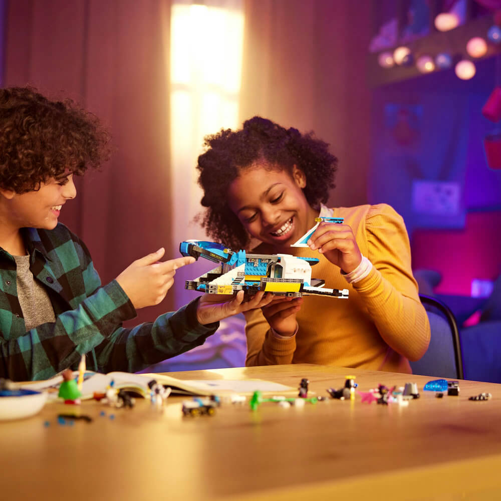 Two kids building the LEGO® DREAMZzz™ Mr. Oz’s Spacebus 71460 Building Toy Set for Kids (878 Pieces)