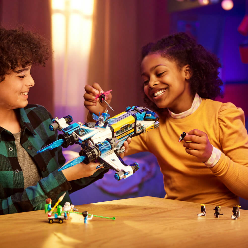 Two kids smiling and playing with the LEGO® DREAMZzz™ Mr. Oz’s Spacebus 71460 Building Toy Set for Kids (878 Pieces)