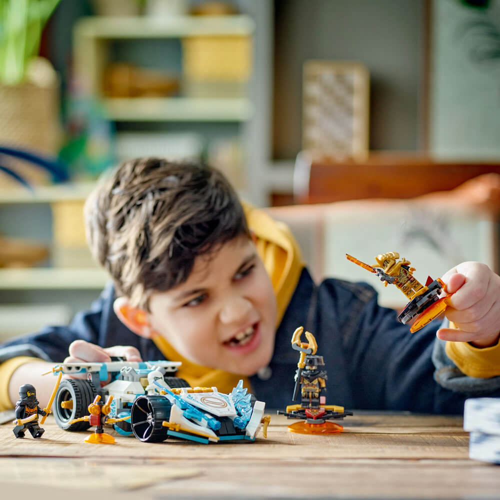 Child shown playing with the LEGO® NINJAGO® Zane’s Dragon Power Spinjitzu Race Car 71791 Building Toy Set (307 Pieces)