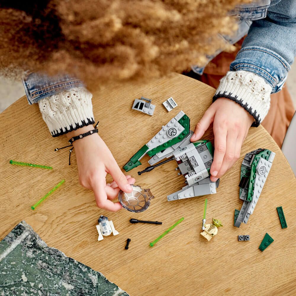 Two hands shown bulding the LEGO® Star Wars™ Yoda’s Jedi Starfighter™ 75360 Building Toy Set (253 Pieces)