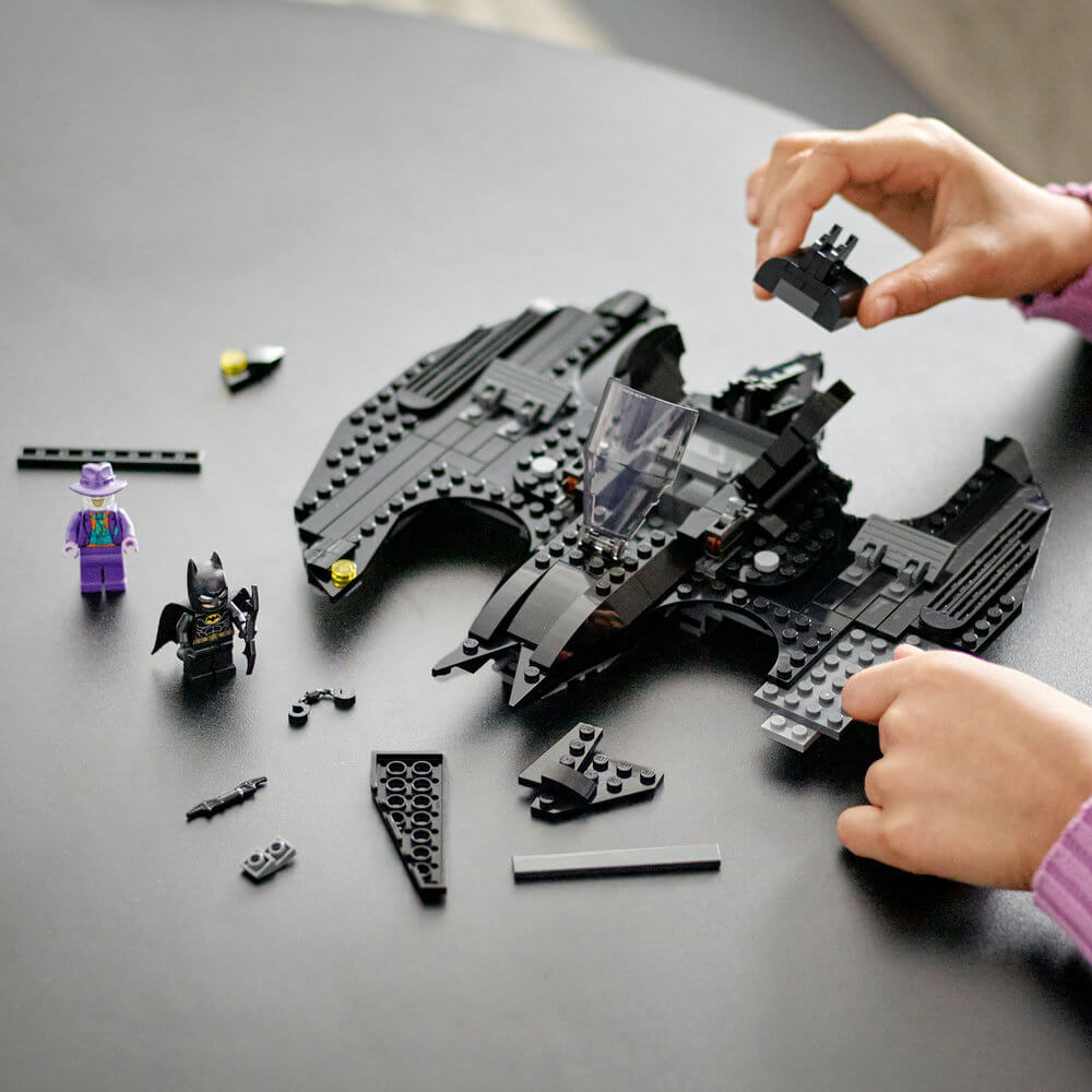 Two hands building the LEGO® DC Batwing: Batman™ vs. The Joker™ 76265 Building Toy Set (357 Pieces)
