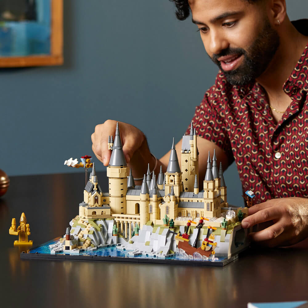 Adult shown building the LEGO® Harry Potter Hogwarts™ Castle and Grounds 2660 Piece Building Set (76419)