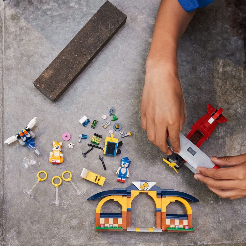 Two hands shown building the LEGO® Sonic the Hedgehog™ Tails’ Workshop and Tornado Plane 76991 (376 Pieces)