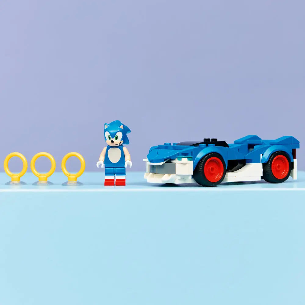 Completed LEGO Sonic the Hedgehog Speedster Lightning model car in blue and white plastic with sleek racing body, red wheels, Sonic minifigure, and gold rings, displayed neatly on a smooth tabletop background.