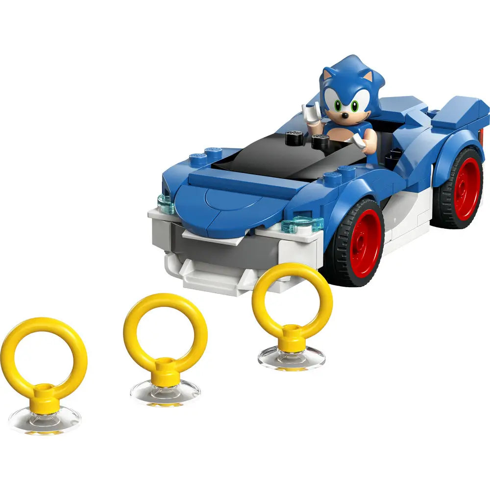 LEGO Sonic the Hedgehog Speedster Lightning car in bright blue and white plastic with smooth curved panels, low sporty shape, red wheels, and Sonic minifigure seated inside, shown with collectible gold rings on a white background.