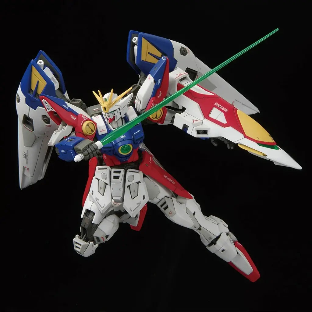 Bandai RG Wing Gundam Zero model kit action pose shows the figure lunging forward with green beam saber raised, wing shields flared wide and colorful armor panels emphasized by sharp lighting on black.