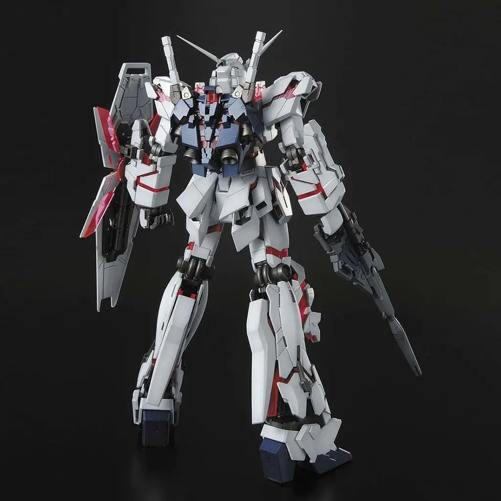 Bandai RX-0 Unicorn Gundam model kit rear view displaying white armor panels, mechanical joints, shield mount, and rifle, posed on a dark background to showcase build details and articulated frame.