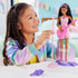 Barbie 65th Anniversary Pop Star Doll set shows a smiling child in a rainbow jacket playing with the doll dressed in a pastel swirl dress, pink guitar, and stage microphone.