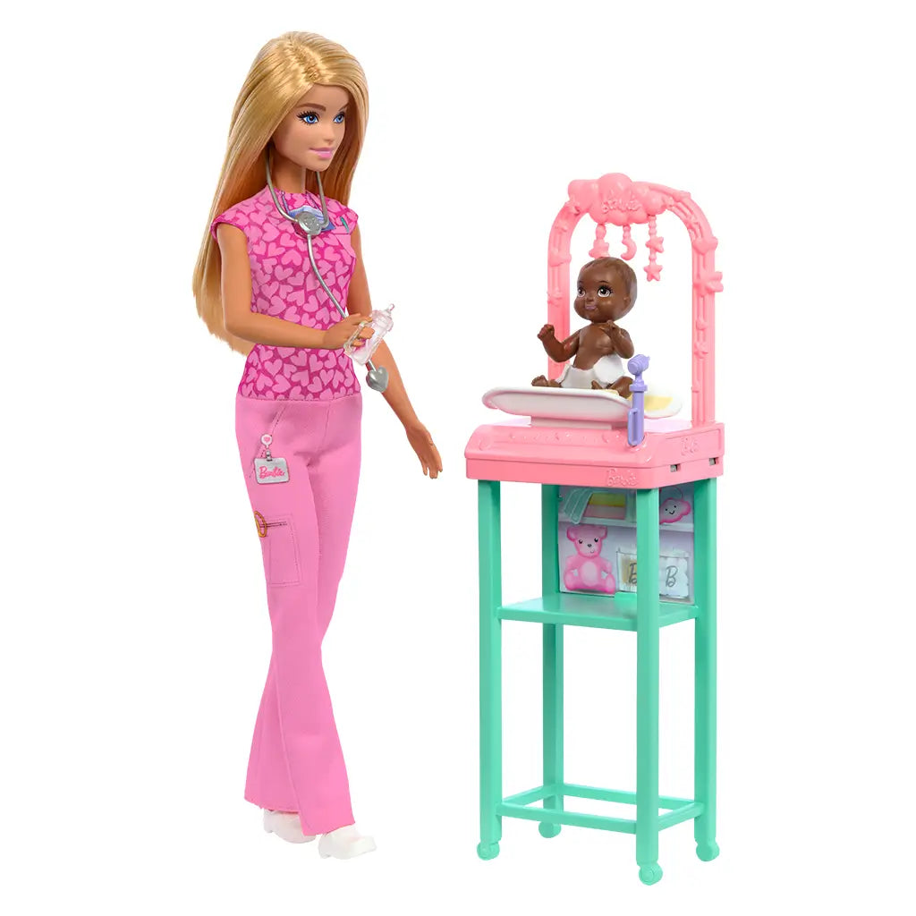 Barbie baby doctor doll in pink scrubs with stethoscope holds bottle while standing beside pastel pink and teal exam table, caring for an infant doll in a nursery-themed playset.