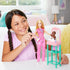 Smiling young girl plays with Barbie baby doctor doll dressed in pink scrubs and nursery station, engaging with infant doll in diaper for realistic medical role-play fun.