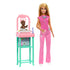 Barbie baby doctor doll in bright pink scrubs with heart print top stands beside a pastel pink and teal nursery station caring for an infant doll, showcasing role-play medical accessories.