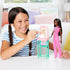 Smiling child plays with Barbie Baby Doctor set, using accessories to care for baby doll in pink and teal nursery station, encouraging imaginative roleplay and nurturing skills.