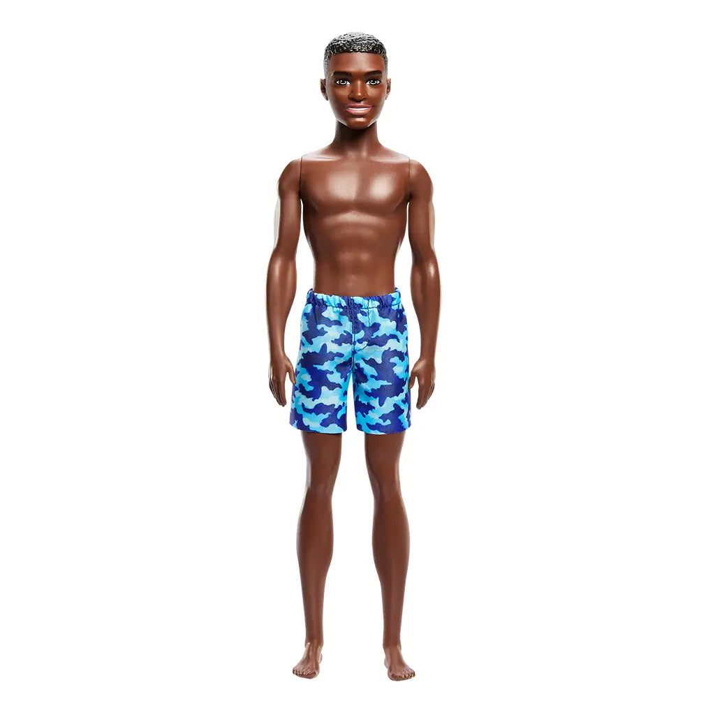 Front view of Barbie Beach Ken doll standing barefoot, wearing blue camouflage swim shorts, with short brown textured hair and a smiling facial expression.