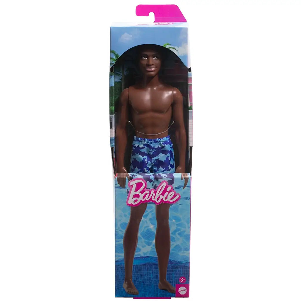 Barbie Beach Ken doll in retail packaging, wearing blue camouflage swim shorts, posed against a poolside backdrop with Barbie logo and palm tree illustrations.
