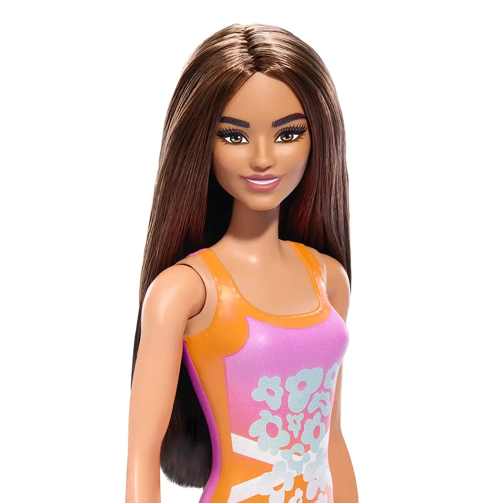 Barbie Fashion doll with long brown hair wearing a sleeveless orange and pink dress featuring white floral patterns. Ideal for imaginative play and collecting. Perfect gift for children who love dolls.