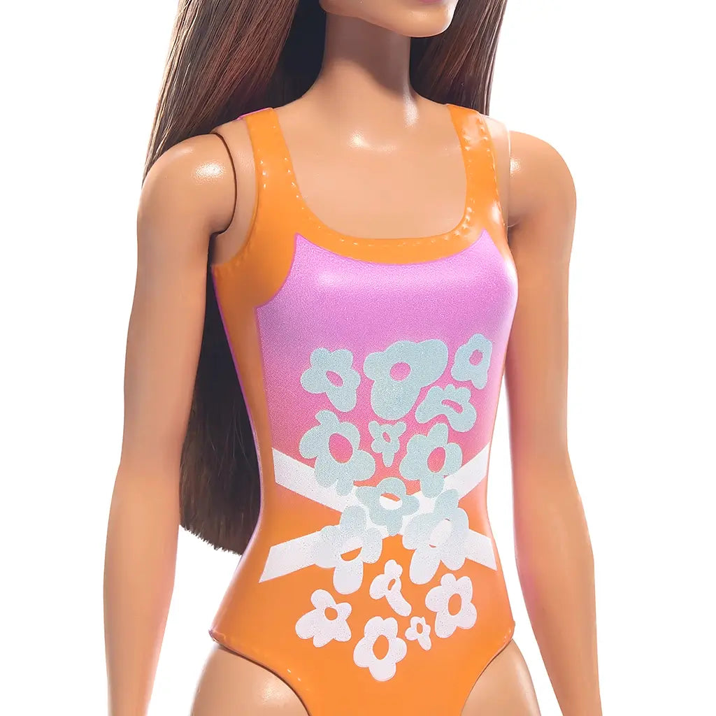 Barbie doll in orange and pink floral swimsuit with white crisscross bands, shown from shoulders down. Long brown hair. Great for beach-themed pretend play and doll collectors.