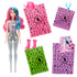 Barbie Color Reveal doll with pink and blue hair stands beside colorful surprise bags containing a pink cowboy hat, boots, necklace, and pink-blue patterned skirt accessories.