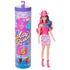 Barbie Color Reveal doll with pink and blue hair wears a pink cowboy hat, pink boots, and pink-blue patterned skirt, posed next to its tall purple-lidded cylindrical package.