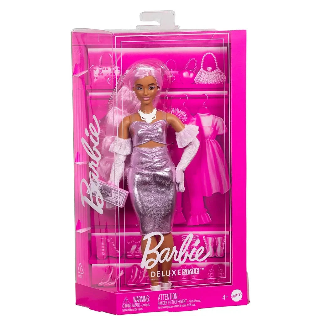 Barbie Deluxe Style doll in packaging, featuring long pink hair, shiny ruched pink dress, white boots, matching gloves, and pink money-themed clutch.