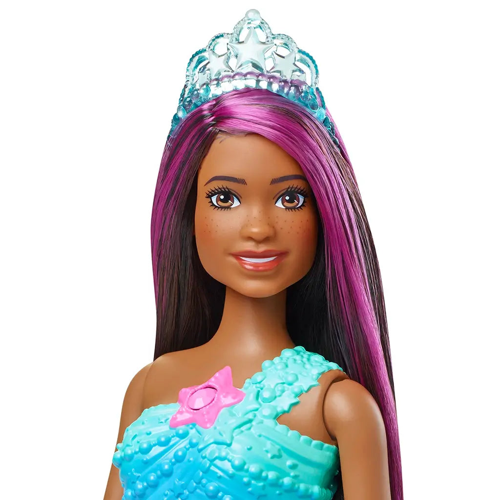 Close-up of Barbie Dreamtopia Twinkle Lights Mermaid doll showing her smiling face, long dark hair with magenta streaks, silver tiara, and textured blue top with pink star.
