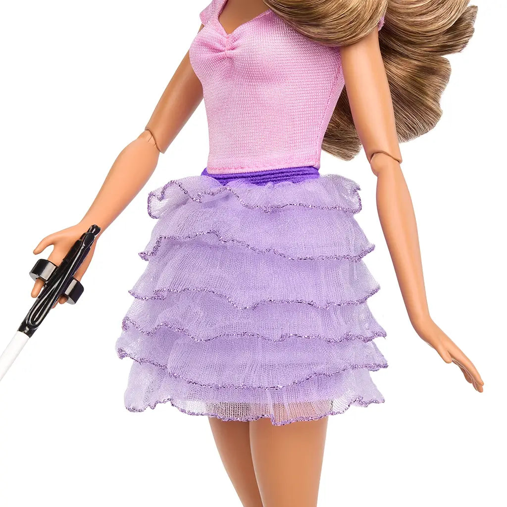 Close-up of Barbie Fashionistas doll outfit featuring a fitted pink top with ruched neckline and a layered purple ruffled skirt with glitter edges, held at the waist with a purple belt.