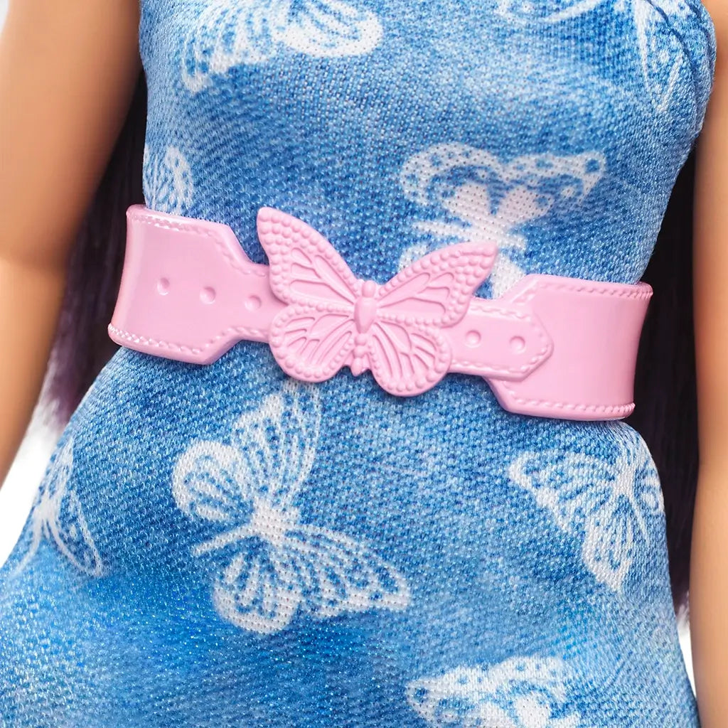 Close-up of Barbie Fashionistas doll’s denim butterfly-print dress with pink molded belt featuring a raised butterfly buckle at the center.