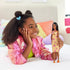 Smiling young girl plays with Barbie Fashionistas 233 doll wearing a yellow and white checkered midi dress with pink flowers and orange platform sandals.