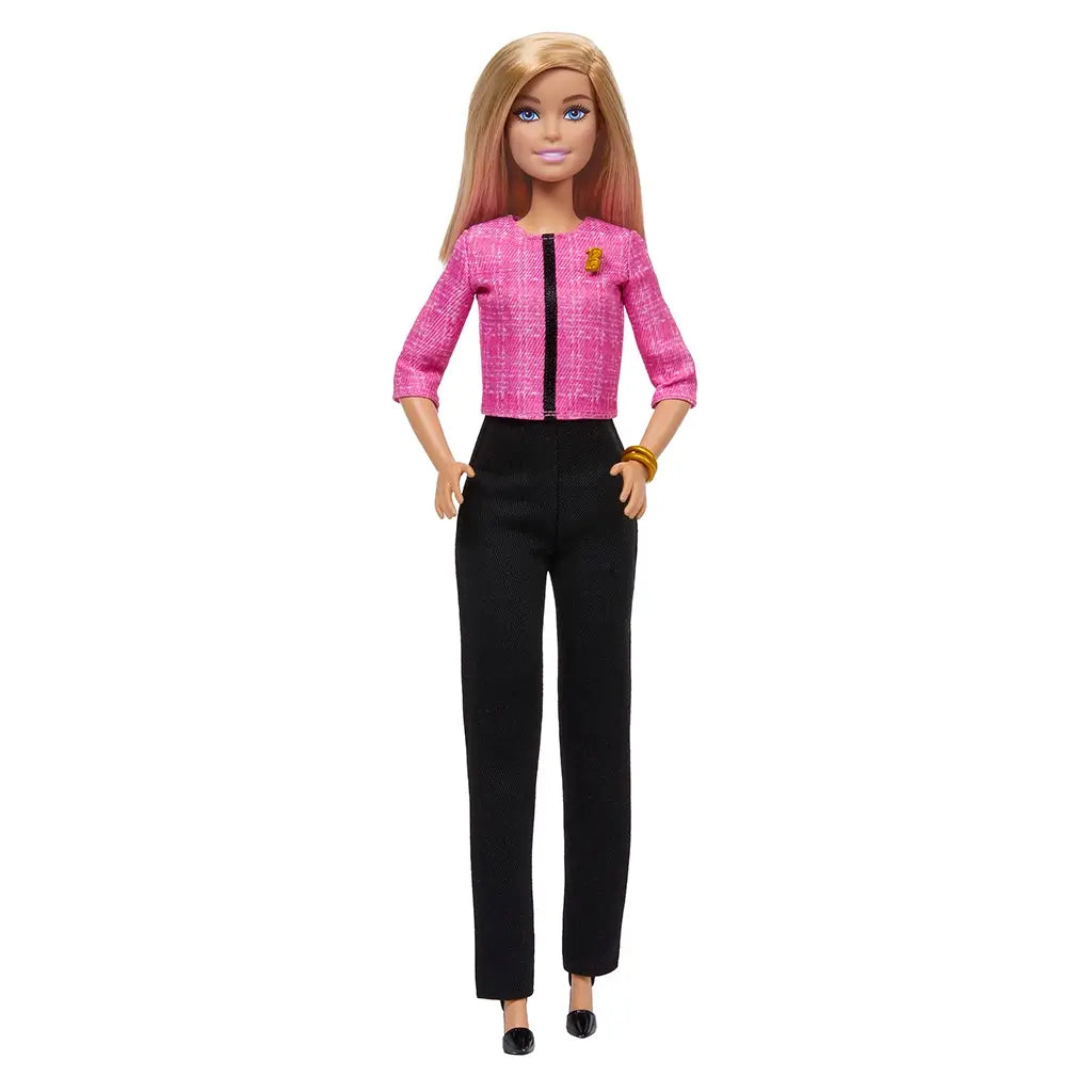 Front-facing view of Barbie Future Leader doll wearing pink jacket and black trousers with gold bracelet, styled with blonde hair and black shoes, designed for empowerment play.