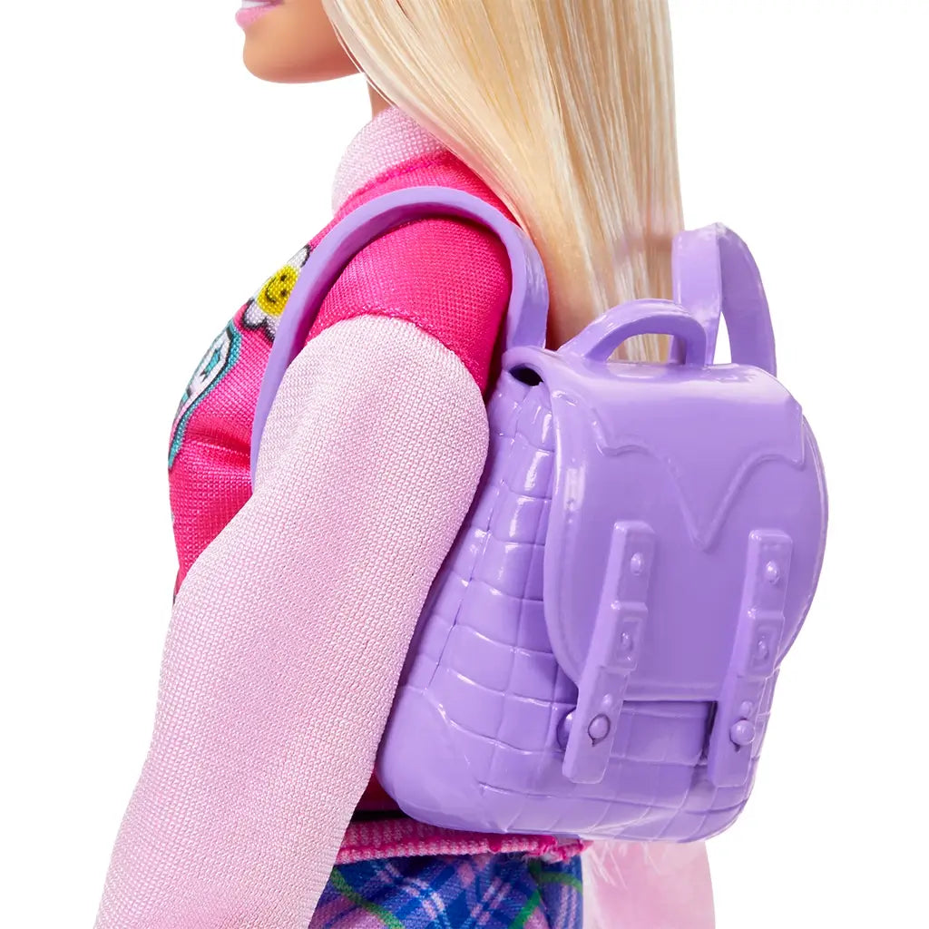 Close-up of Barbie doll wearing a textured lilac backpack with buckle details, paired with her bright pink jacket and plaid skirt, designed for back-to-school storytelling play.