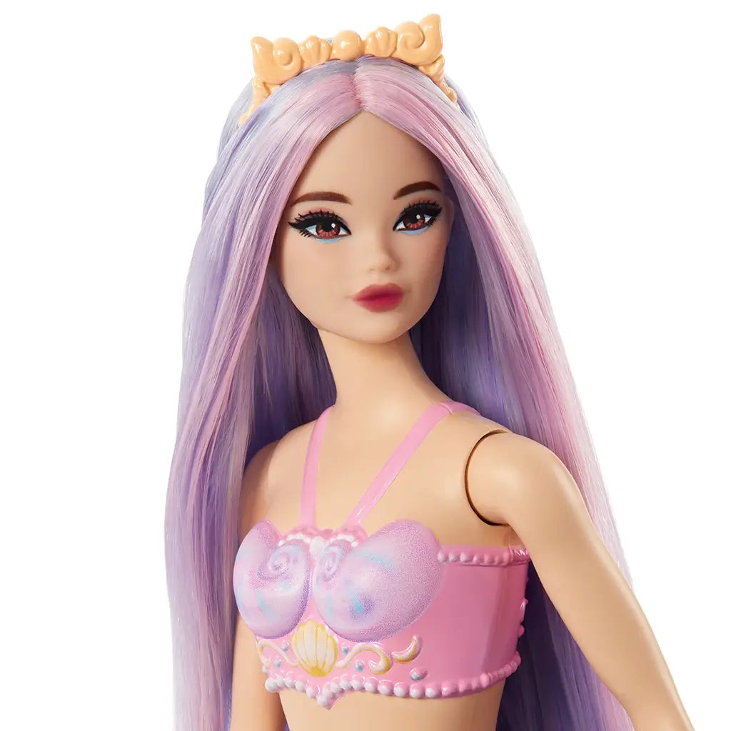 Closeup of Barbie mermaid doll’s face, highlighting her lilac hair with pink streaks, golden crown, red lipstick, and pink seashell top with pearl trim. Designed for imaginative play, this Barbie mermaid doll blends colorful fantasy details with a shimmering aquatic theme, perfect for collectors or kids.