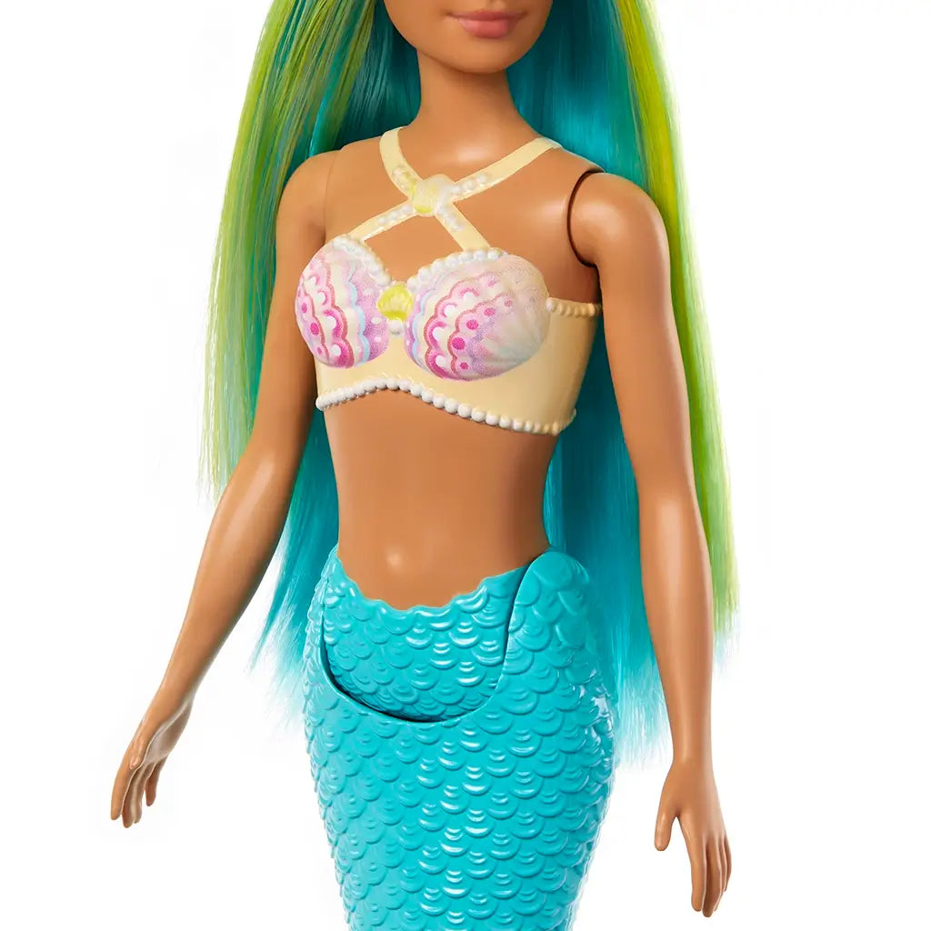 Close-up of Barbie mermaid doll’s outfit featuring a yellow and white seashell-inspired top with pearl details, paired with a sculpted turquoise mermaid tail.